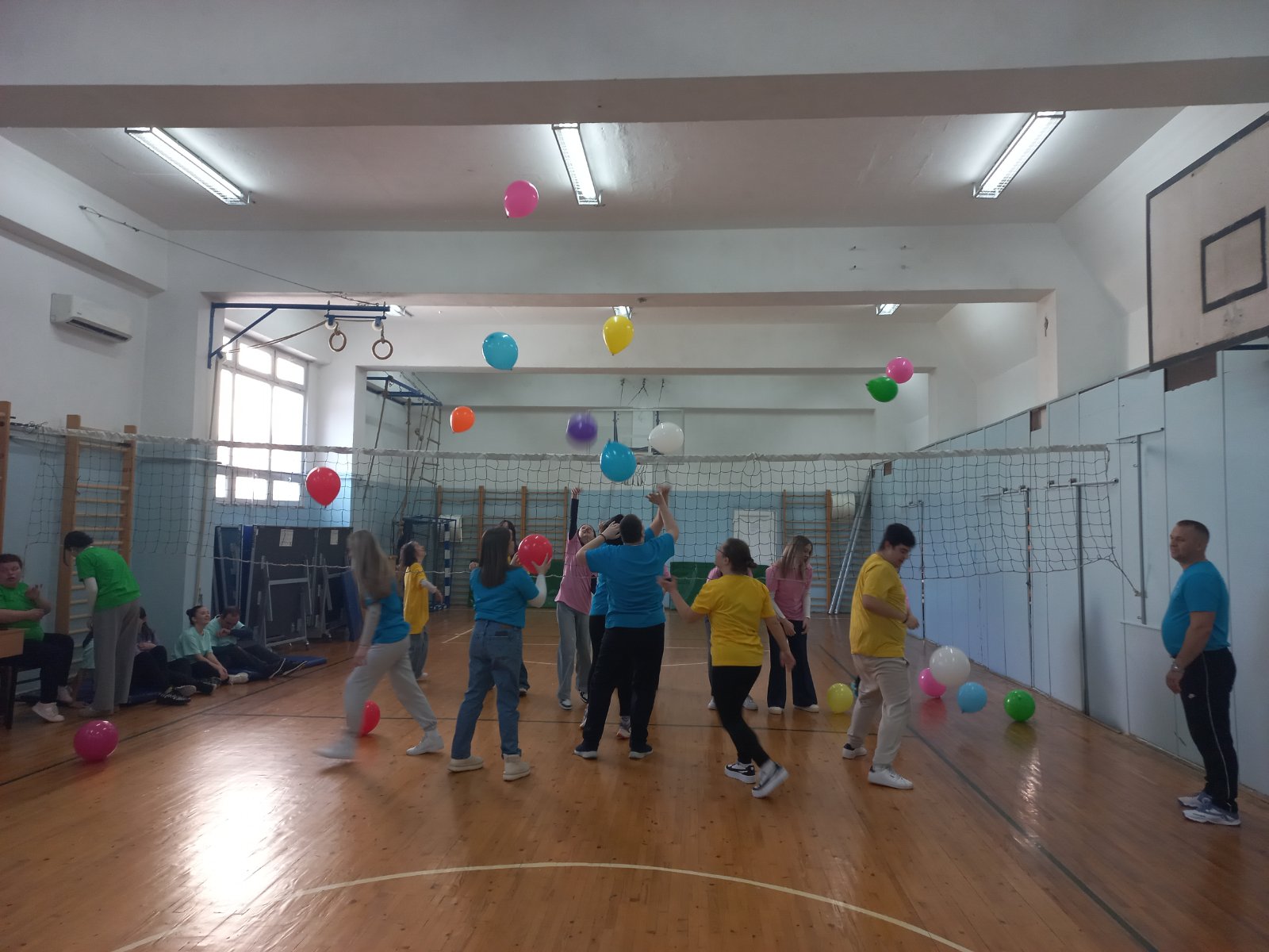 Participants playing an inclusive balloon game over a volleyball net in a gymnasium in North Macedonia
