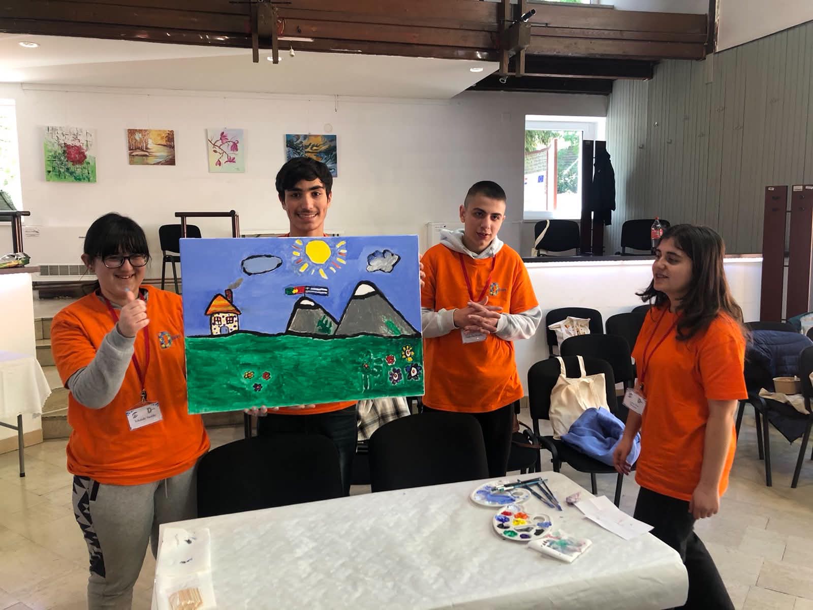 Participants in orange t-shirts presenting a completed landscape painting during the Special (Olympic) Games in Croatia
